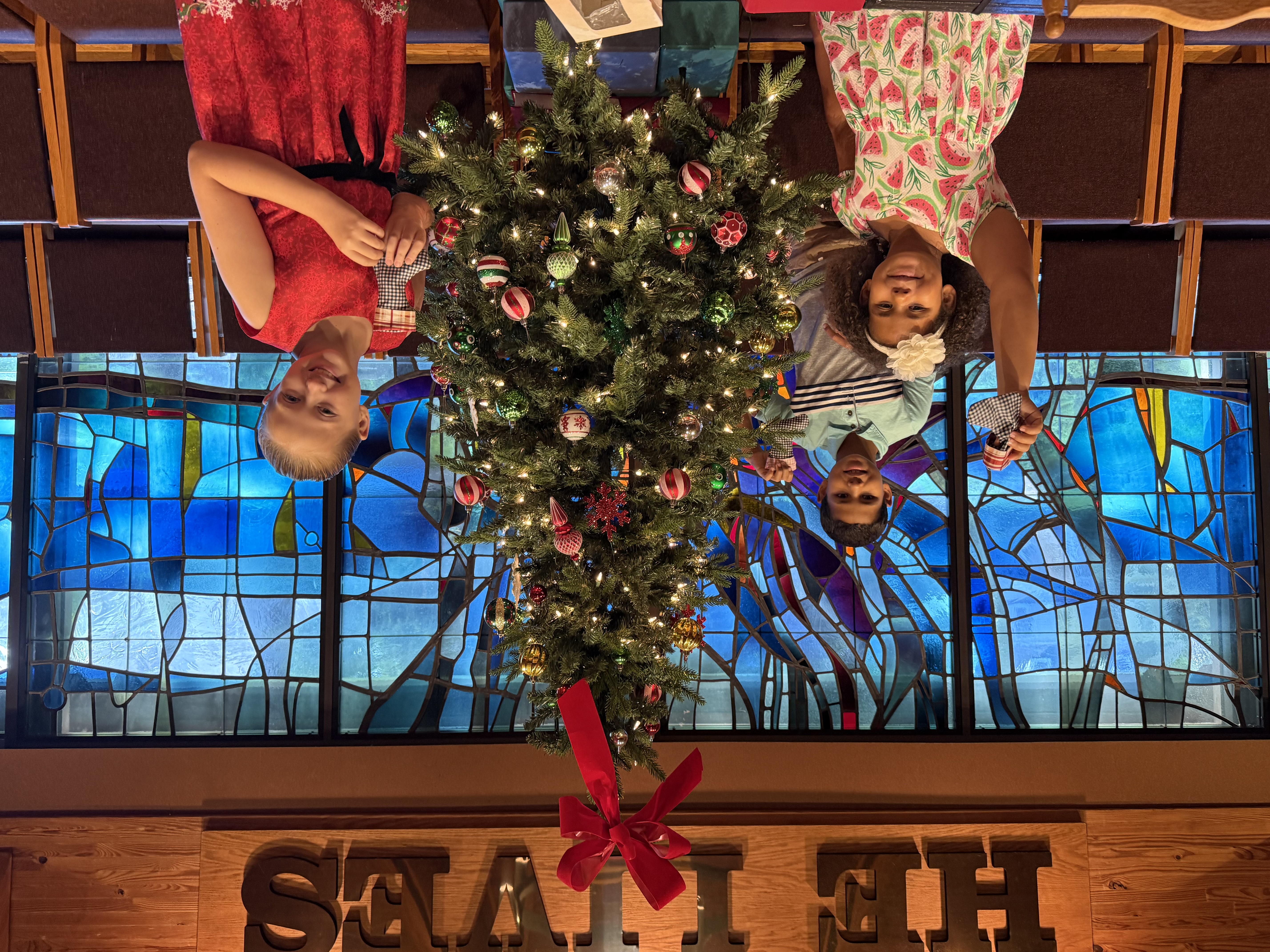 Children holding handmade stocking ornaments by the Christmas tree