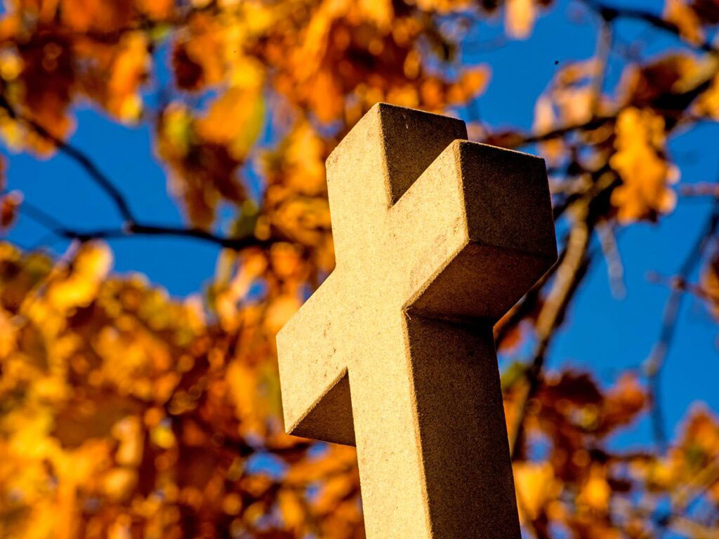 Stone cross against autumn leaves