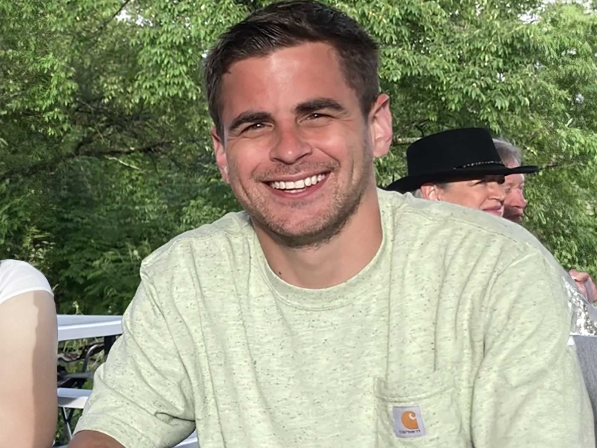 The fully restored stained glass panel featuring a white cross with a jeweled crown at its center, surrounded by intricate scrollwork in rich jewel tones of amber, ruby, and navy, set in a custom barn-wood frame.